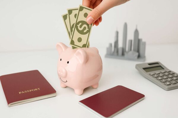 Một con heo đất, hộ chiếu và tiền tệ, minh họa cho việc tiết kiệm chi phí khi xin visa du lịch Hong Kong.
