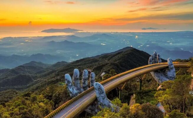 Hình ảnh Cầu Vàng nổi tiếng ở Bà Nà Hills hiện ra mờ ảo trong sương sớm, được nâng đỡ bởi đôi bàn tay đá khổng lồ