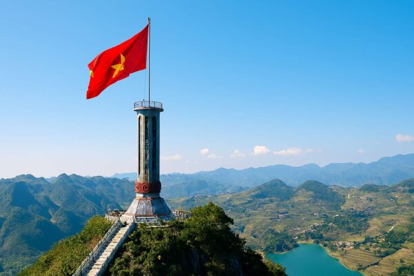 Cột cờ Lũng Cú, điểm cực Bắc của Việt Nam, với lá cờ đỏ sao vàng lớn tung bay kiêu hãnh trên nền trời xanh.