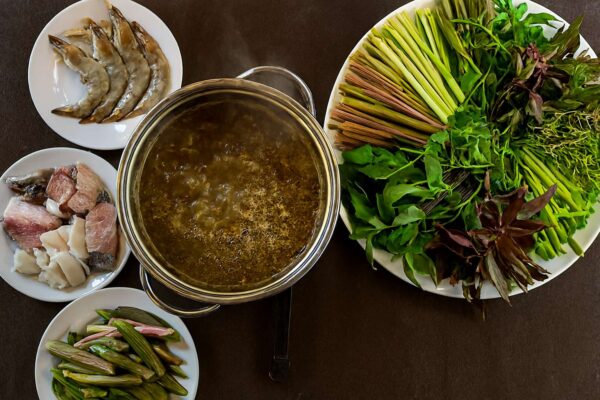 Một nồi lẩu mắm Cần Thơ đầy ắp, sôi sục, xung quanh là đĩa hải sản tươi và mẹt rau miệt vườn đa dạng với hơn 20 loại.